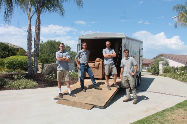 Four Spry Movers crew members beside a moving truck and loading ramp